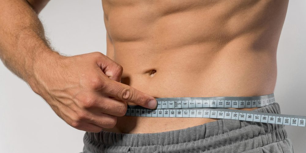 homem-em-forma-segurando-a-fita-metrica-na-cintura